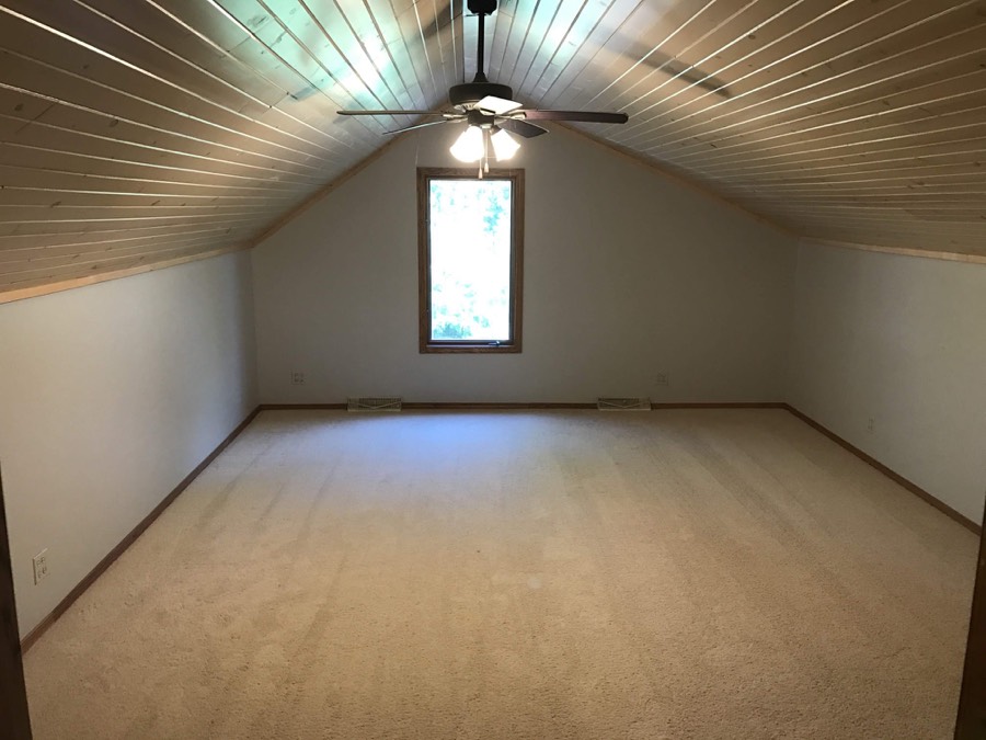Freshly painted bonus room with vaulted wood ceiling and ceiling fan